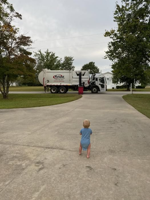 Young child watching a Ryland Environmental truck drive by
